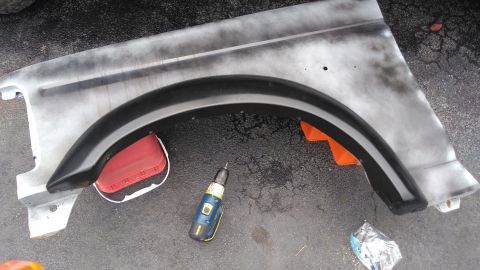 1996 Ford Bronco - A vehicle fender, possibly undergoing repair or modification, is shown with a drill and reflector.