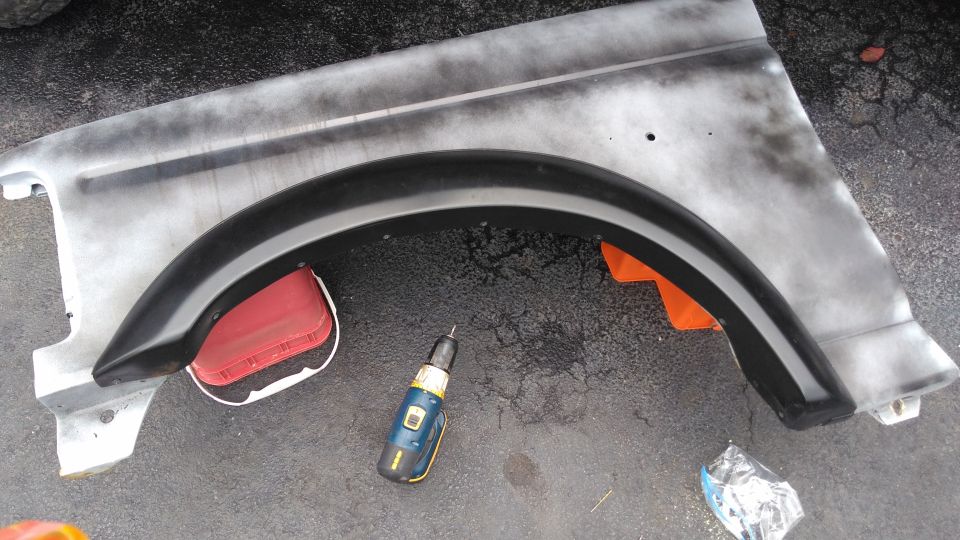 Gray fender with black trim and red reflector, a drill sits nearby