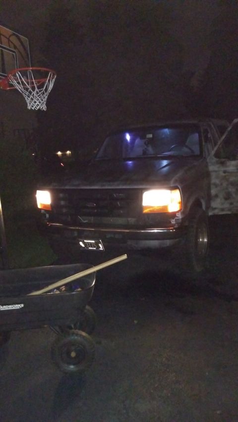 1996 Ford Bronco - Front view of a 1996 Ford Bronco parked outdoors at night with headlights on.