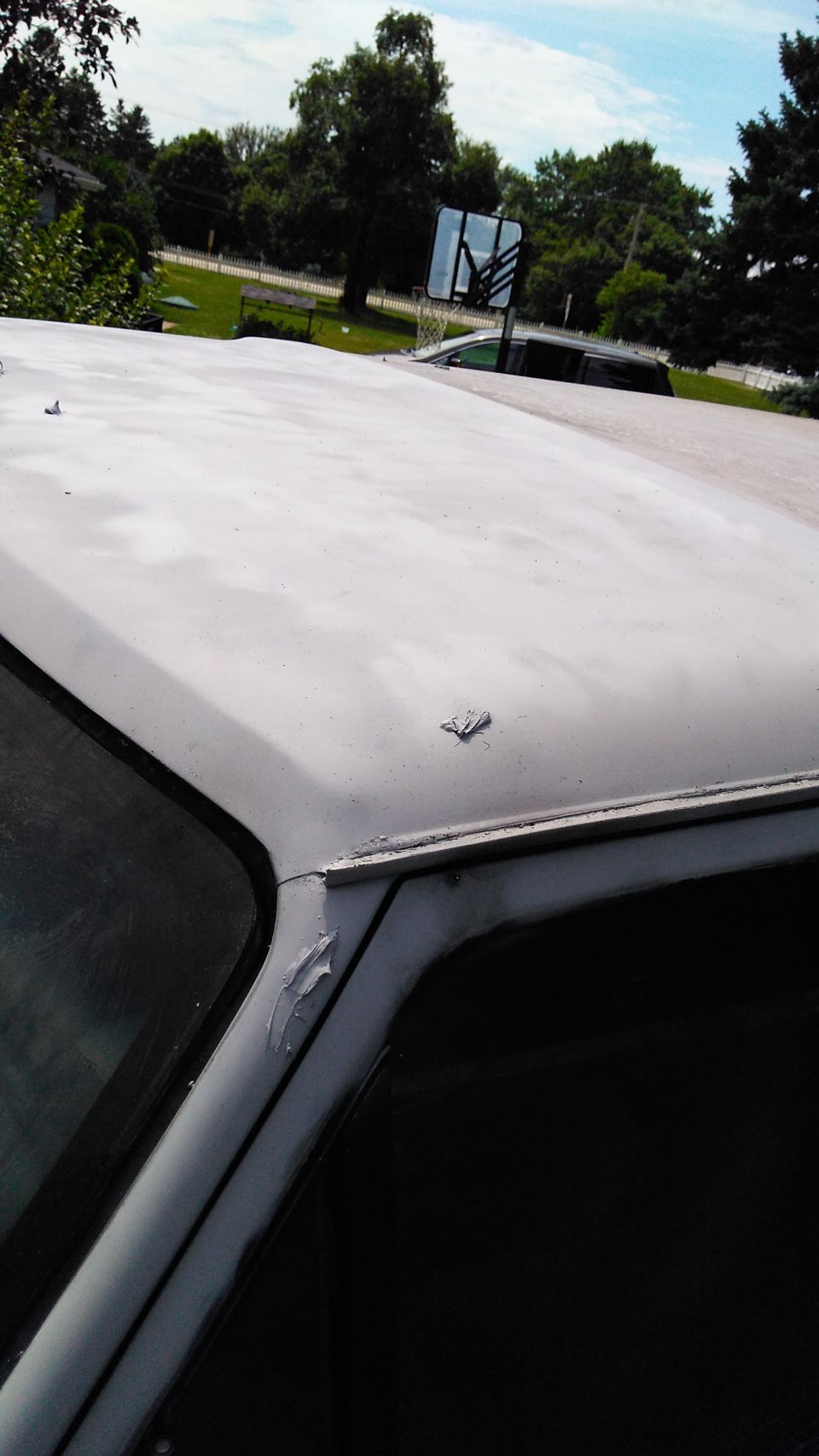 Gray primer on car roof, showing damage near the window frame