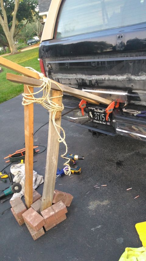 1996 Ford Bronco - The rear of a black 1996 Ford Bronco is shown with a temporary wooden support structure and clamps attached to the bumper area.