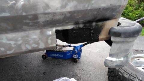 1996 Ford Bronco - Vehicle body panel undergoing repair with a hydraulic jack supporting the frame.