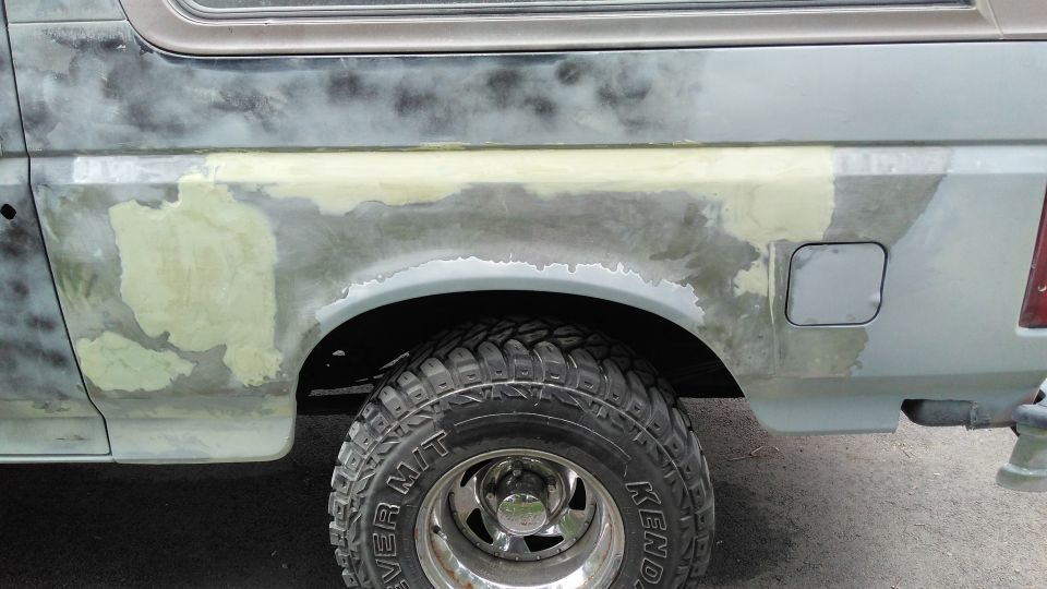 Side view of a Ford Bronco with body filler and primer on the rear quarter panel