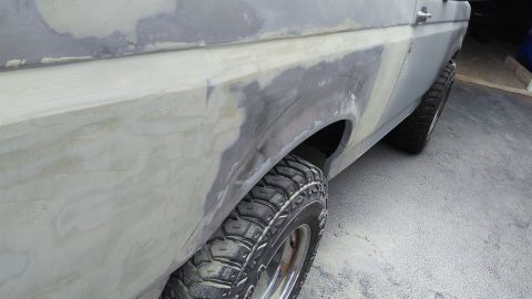 1996 Ford Bronco - Body filler being applied to the rear fender of a 1996 Ford Bronco during bodywork.