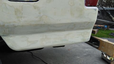 1996 Ford Bronco - The rear section of a vehicle is shown with body filler applied, indicating preparation for repair or painting.