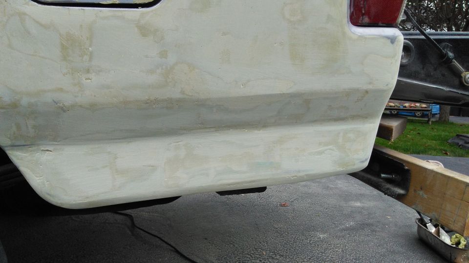 rear bumper area of a vehicle being prepped for paint, showing body filler