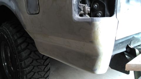 1996 Ford Bronco - A close-up of a vehicle's rear bumper undergoing body work, with a tire visible.