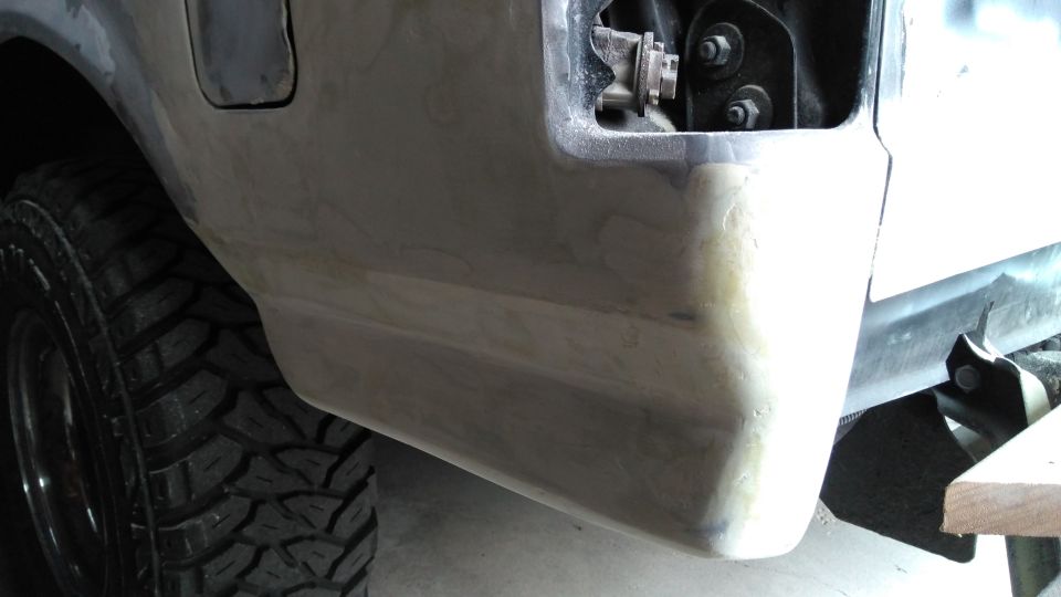 Rear bumper section with body filler and a large off-road tire