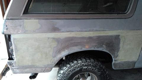 1996 Ford Bronco - This vehicle's rear quarter panel is shown with body filler and primer, indicating preparation for paint work.