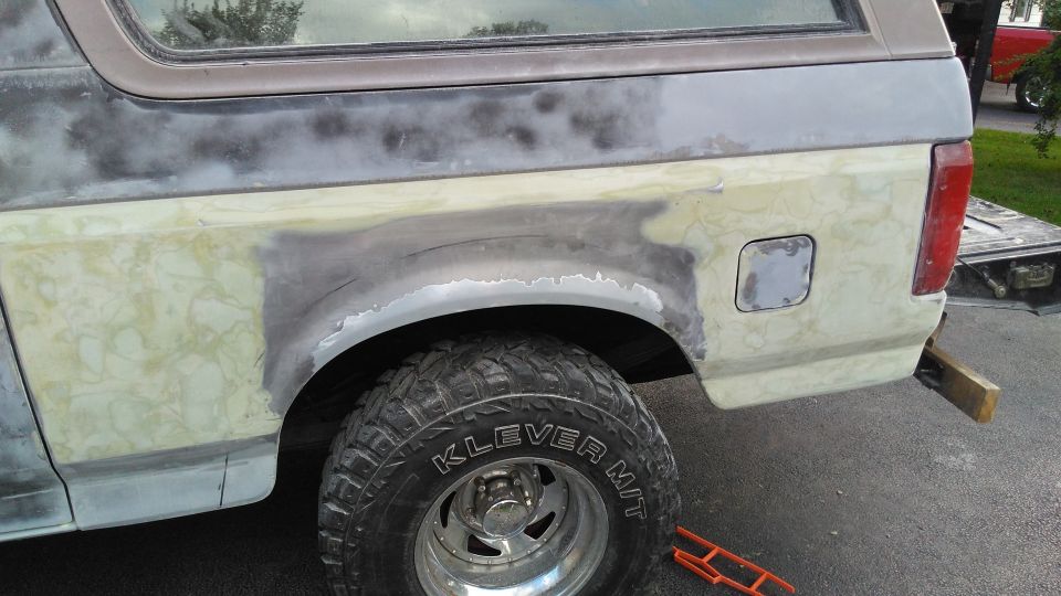 Rear quarter panel of a 1992 Ford Bronco undergoing body repair, showing primer and filler