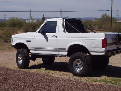 1993 Ford Bronco - White lifted 1993 Ford Bronco with roll cage parked outdoors.