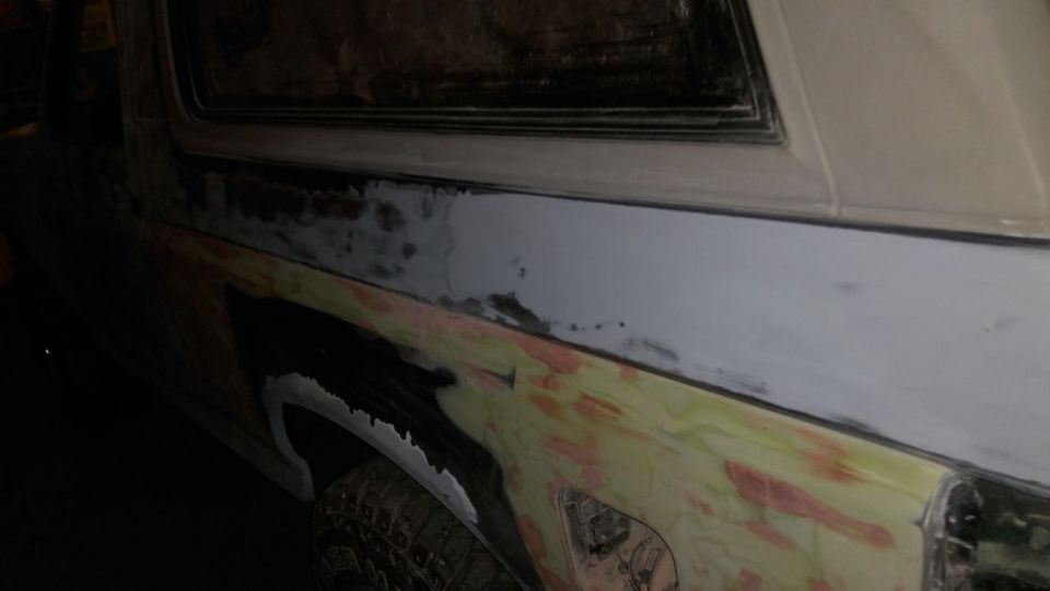 Side view of a Ford Bronco undergoing body repair, showing primer and body filler