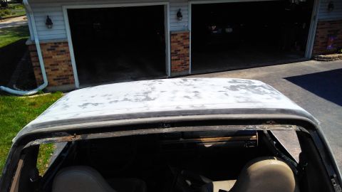 1996 Ford Bronco - The roof of an older vehicle shows significant wear and peeling paint, with a garage visible in the background.