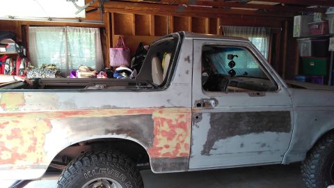 1996 Ford Bronco - This Ford Bronco is undergoing bodywork, showing primer and exposed metal on its side.
