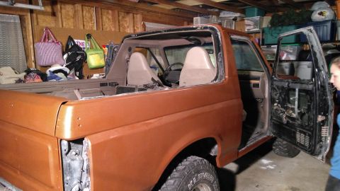 1996 Ford Bronco - An orange SUV is shown with its doors removed, undergoing work in a garage.