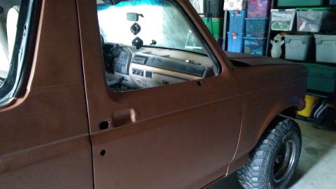 1996 Ford Bronco - The interior of a brown SUV is visible from the side, with storage bins in the background.