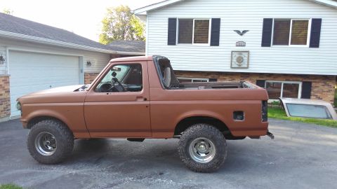 1996 Ford Bronco - This lifted Ford Bronco, with its top removed, is parked in front of a house and garage.