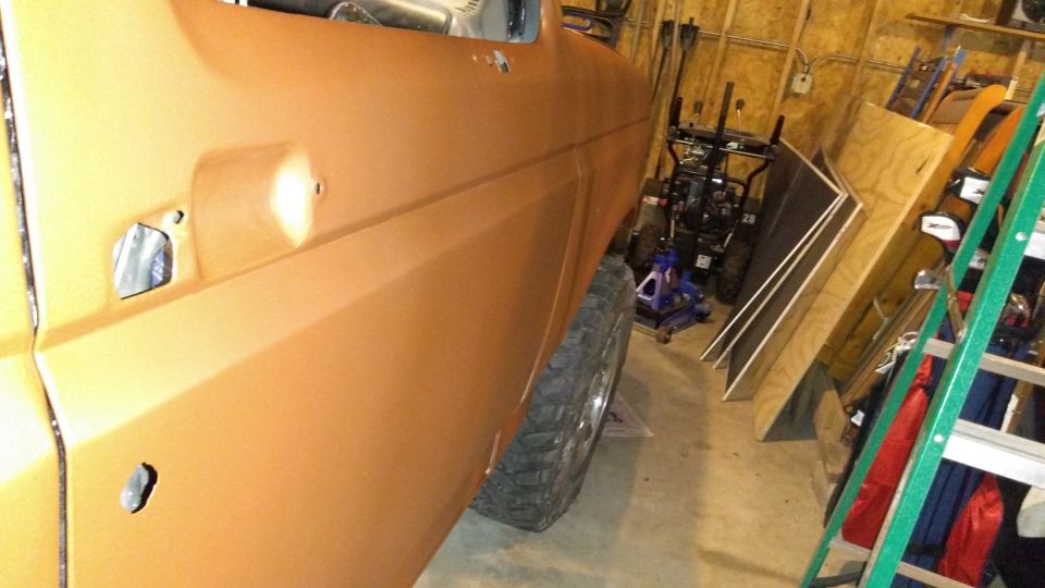 Orange vehicle door and tire in a garage with tools and lumber