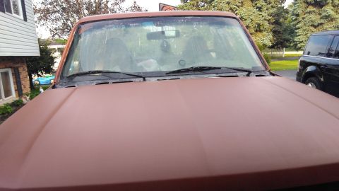 1996 Ford Bronco - The front of a brown Ford Bronco is shown, with a black SUV parked to the right.