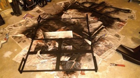 1996 Ford Bronco - Metal components are laid out on newspaper for painting in a garage setting.
