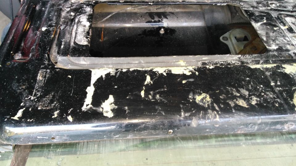 Black tailgate with peeling paint and exposed metal. Part of a vehicle