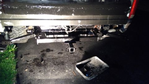 1996 Ford Bronco - The rear of a vehicle is shown, a trailer hitch and a pan on the ground.