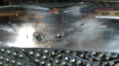 1996 Ford Bronco - This is a close-up view of a chrome bumper, showing scratches and two mounting holes.