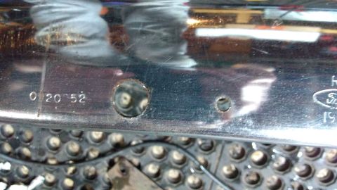 1996 Ford Bronco - A close-up view of a chrome bumper section reveals stamped markings and a partial Ford logo, indicating it is a vehicle part.