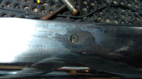 1996 Ford Bronco - Close-up of a chrome bumper section, showing a hole and surface scratches.