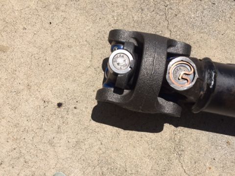 1978 Ford Bronco - A driveshaft part with a Spicer U-joint is shown on a concrete surface.
