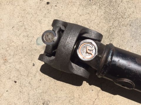1978 Ford Bronco - A driveshaft component, likely a U-joint, is shown resting on a concrete surface. The part has visible grease fittings.