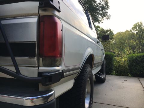 1988 Ford Bronco - Rear view of a white SUV with a chrome bumper and red taillight.