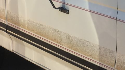 1988 Ford Bronco - Mud splatters obscure the side of a white 1988 Ford Bronco, with visible red and black trim lines.