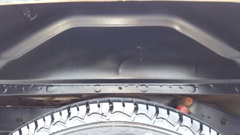 1995 Ford Bronco - The underside of a vehicle, focusing on the spare tire and the surrounding frame and wheel well.