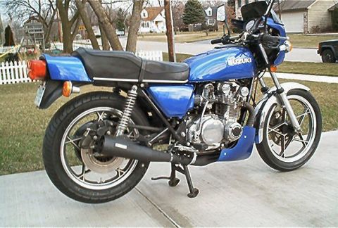 1985 Ford Crown Victoria LTD - Side view of a blue Suzuki motorcycle with a black seat and exhaust pipe.