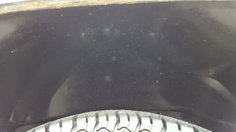 1995 Ford Bronco - Close-up view of a vehicle's wheel well interior, showing tire and some surface imperfections.