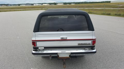 1995 Ford Bronco - Rear view of a silver SUV with a black top, showing its distinctive body style and trim details.