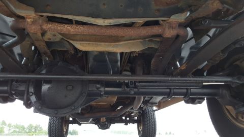 1995 Ford Bronco - The underside of a vehicle is shown, with focus on the rear axle and suspension system.