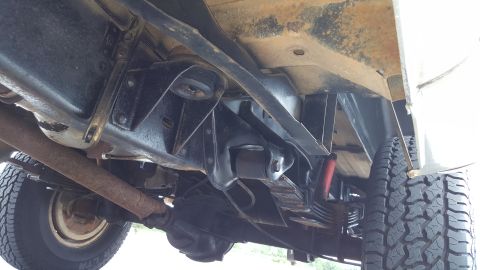 1995 Ford Bronco - The undercarriage of a vehicle is visible, with focus on the rear suspension components and exhaust pipe.