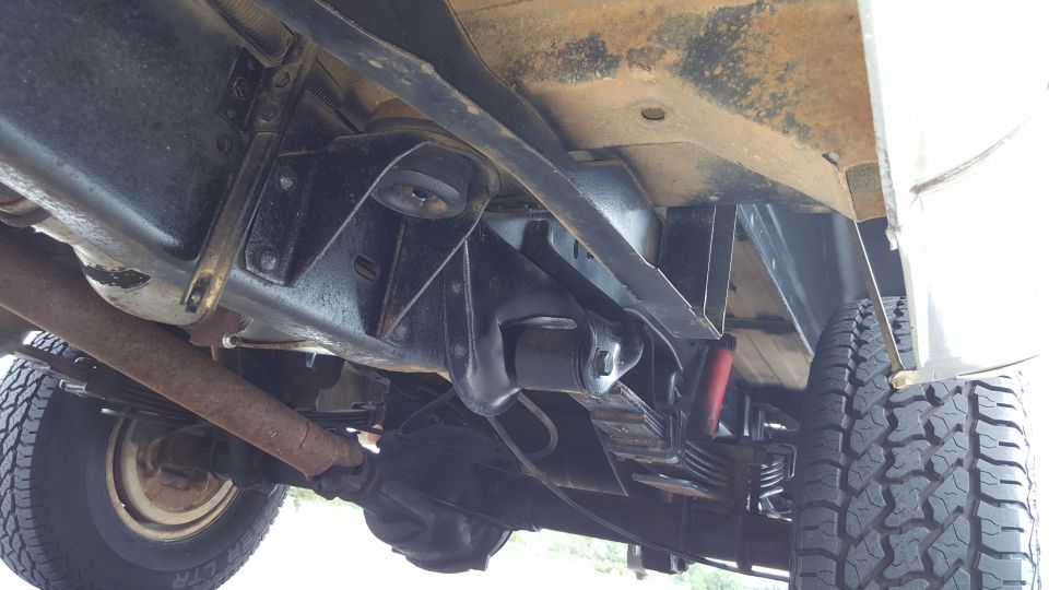 Underside view of a vehicle's suspension and exhaust system, showing leaf springs and a differential
