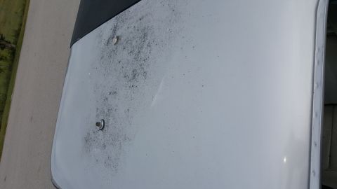 1995 Ford Bronco - Close-up of a white vehicle hood showing dirt and two mounting bolts.