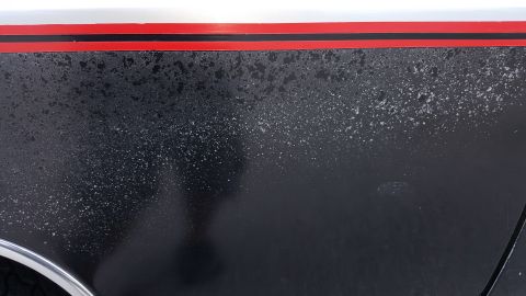 1995 Ford Bronco - Close-up of black paint with a red stripe and speckled texture, showing wear.