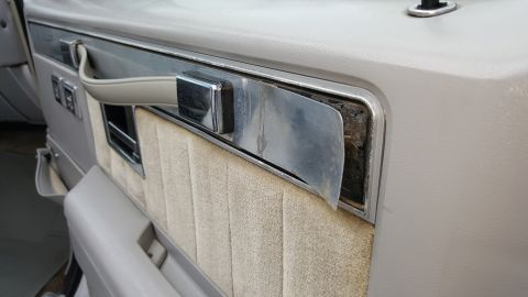 1995 Ford Bronco - Interior door panel detail with fabric upholstery and a chrome pull handle.