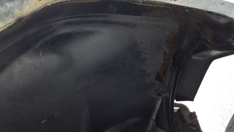 1995 Ford Bronco - Close-up view of a vehicle's wheel well interior, showing extensive rust and corrosion.