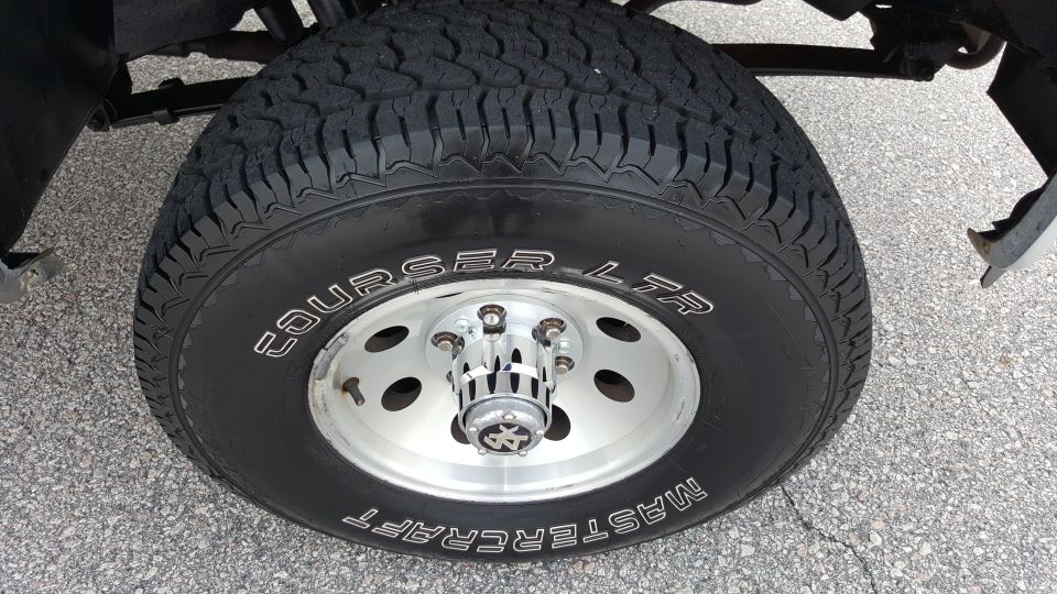 Close-up of a Mastercraft Courser LTR tire on a silver wheel with a chrome hubcap