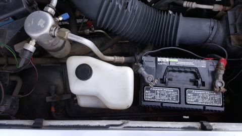 1995 Ford Bronco - Close-up view of engine bay components including the battery and coolant reservoir.