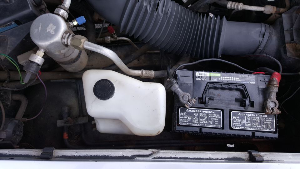 Engine bay with battery, coolant reservoir, and AC components