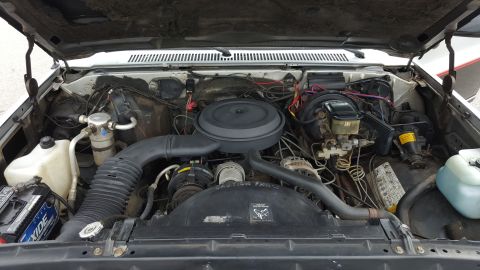 1995 Ford Bronco - The engine bay of a vehicle, showing the V8 engine, air intake system, battery, and various hoses and components.