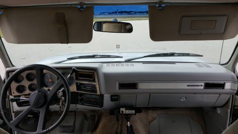 1995 Ford Bronco - The interior of an older truck shows the dashboard, steering wheel, and a view through the windshield.