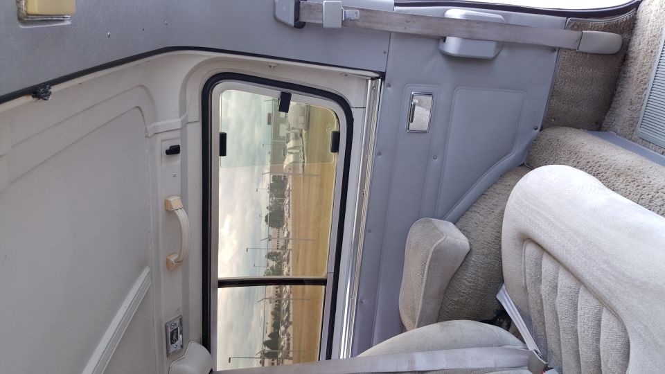 Interior view of a van or RV, showing the door frame, a seat, and carpeted walls